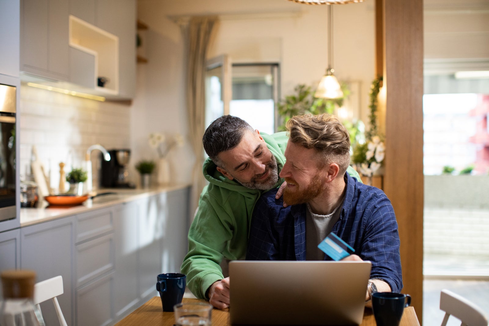 Two people smiling looking at credit card and a laptop