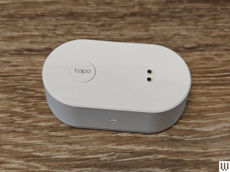 White oval shaped device sitting on wooden surface. Product is branded with the name Tapo.