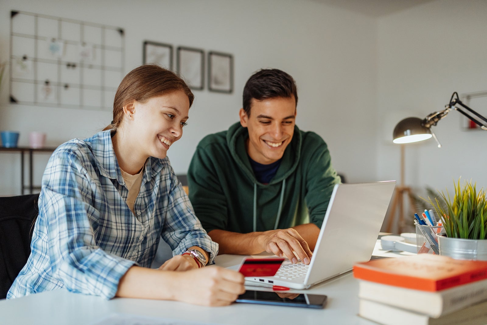 Two people in front of a laptop with a credit card